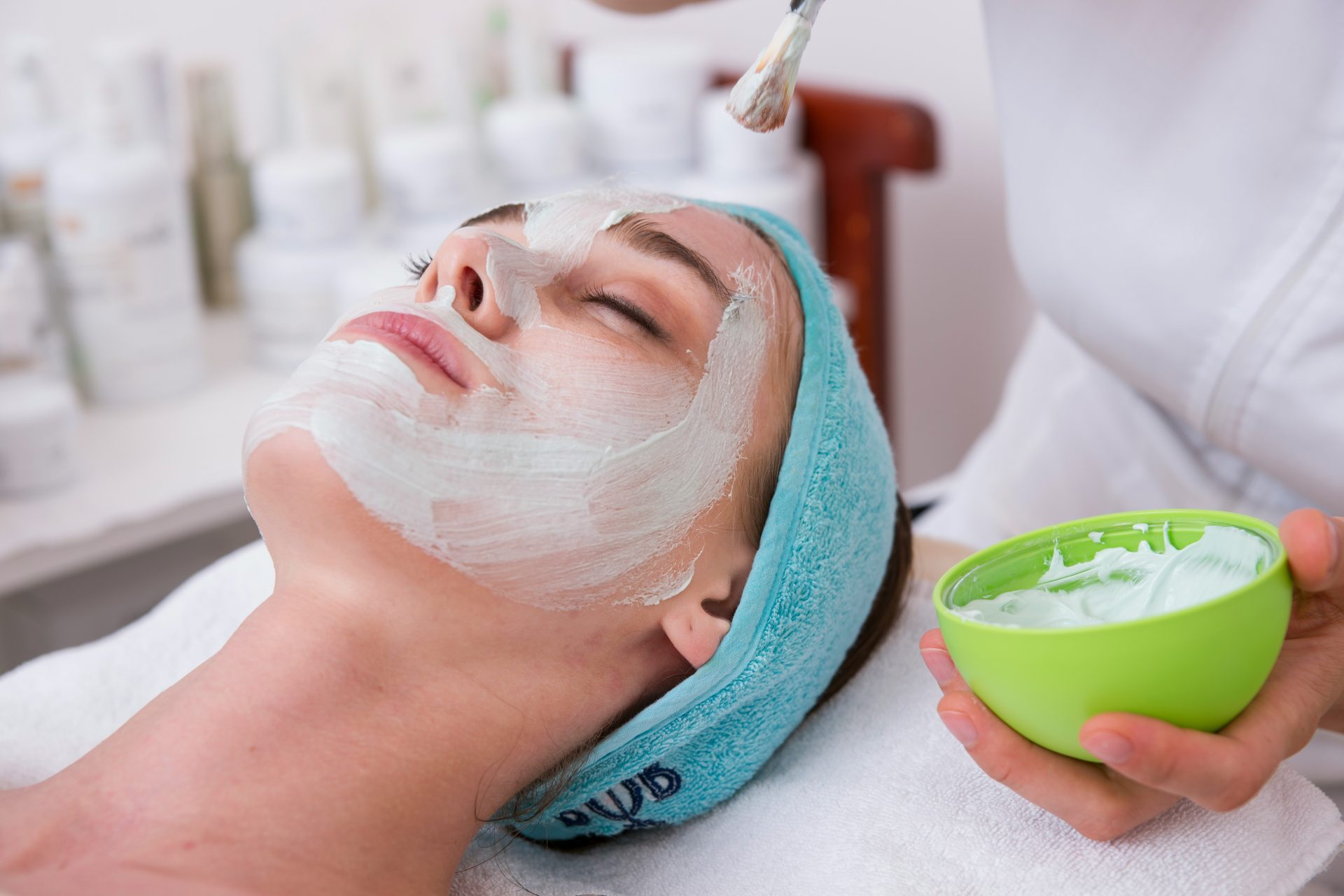 femme allongée sur une serviette bleue avec de la crème blanche sur le visage